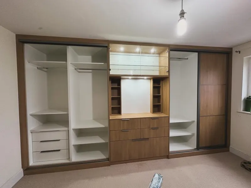 Fitted bedroom wardrobes in white and walnut with a lit dressing table