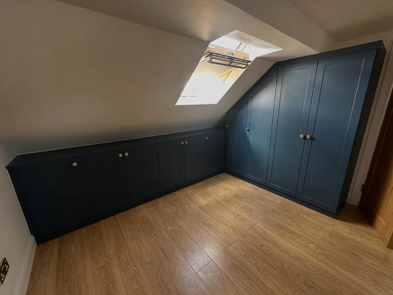 Navy fitted cupboards following the slope of a loft ceiling
