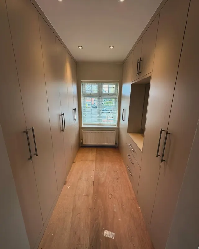 Walk-in wardrobe corridor with a window at the end